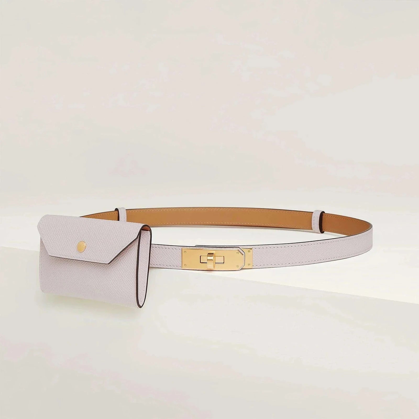 Image of Hermès Kelly belt with minimalist design and golden metallic buckle.