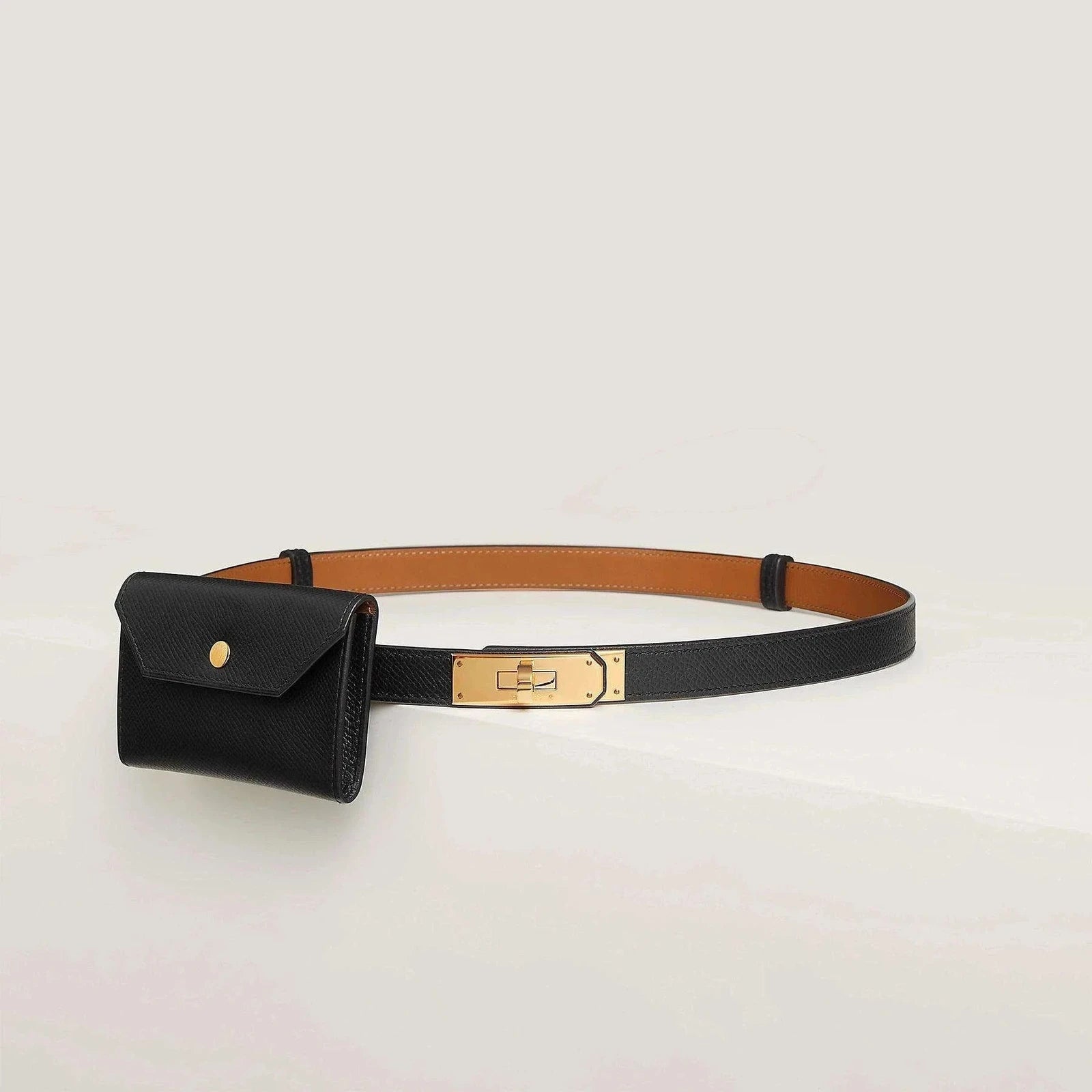 Image of Hermès leather belt with gold buckle and black pouch, luxury fashion accessory.