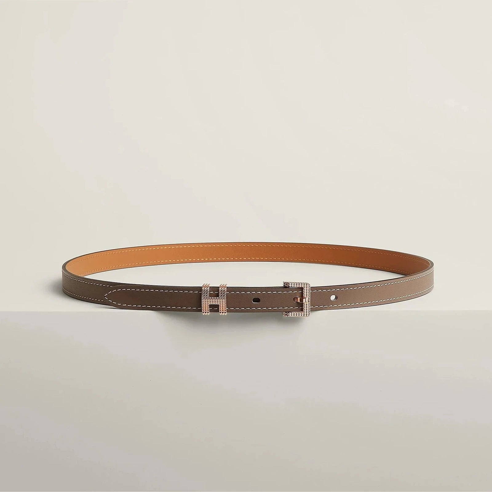 Image of Hermes belt with elegant metallic buckle on white background.