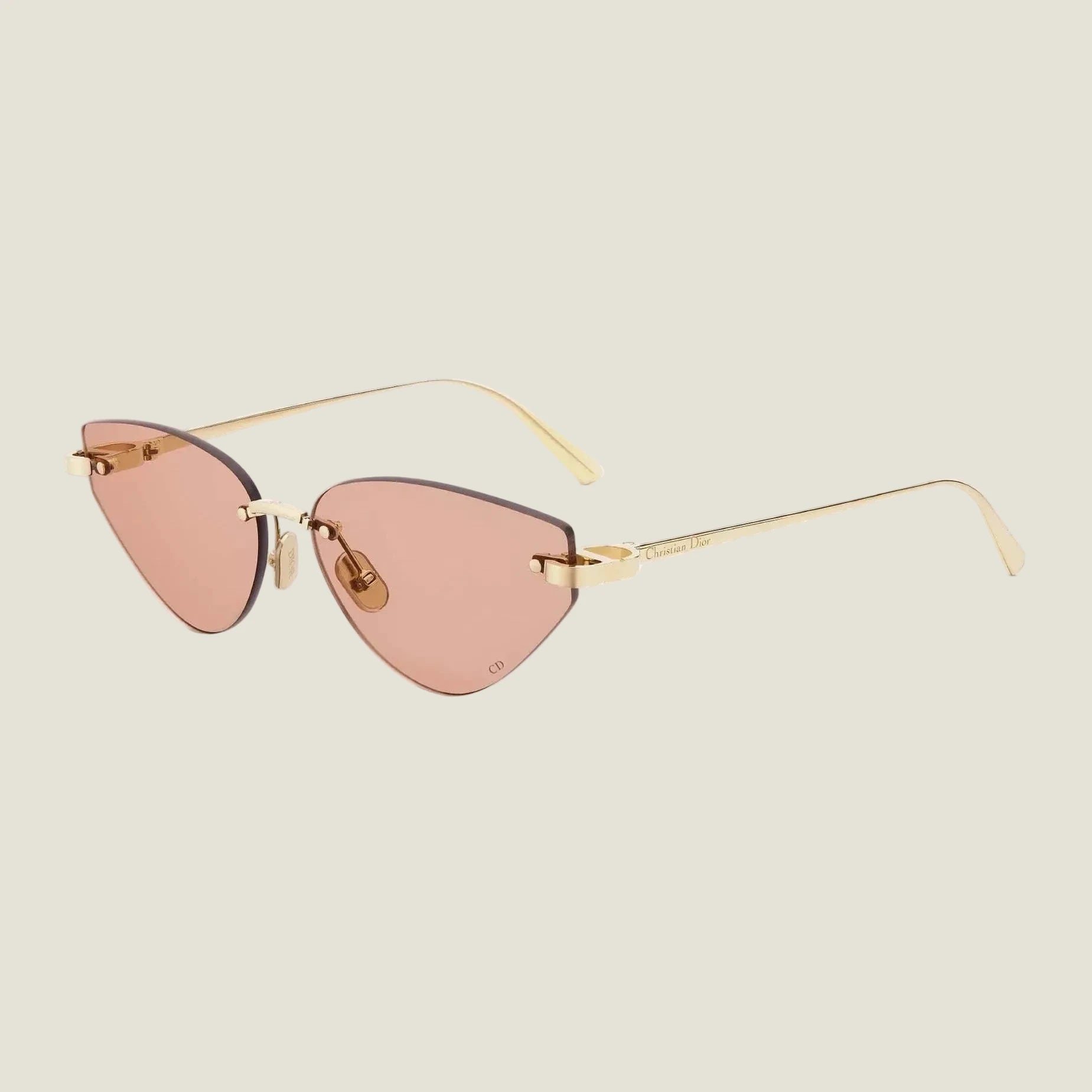 Elegant cat-eye sunglasses with gold frames and rose-tinted lenses, embodying Dior's bold and feminine couture style.