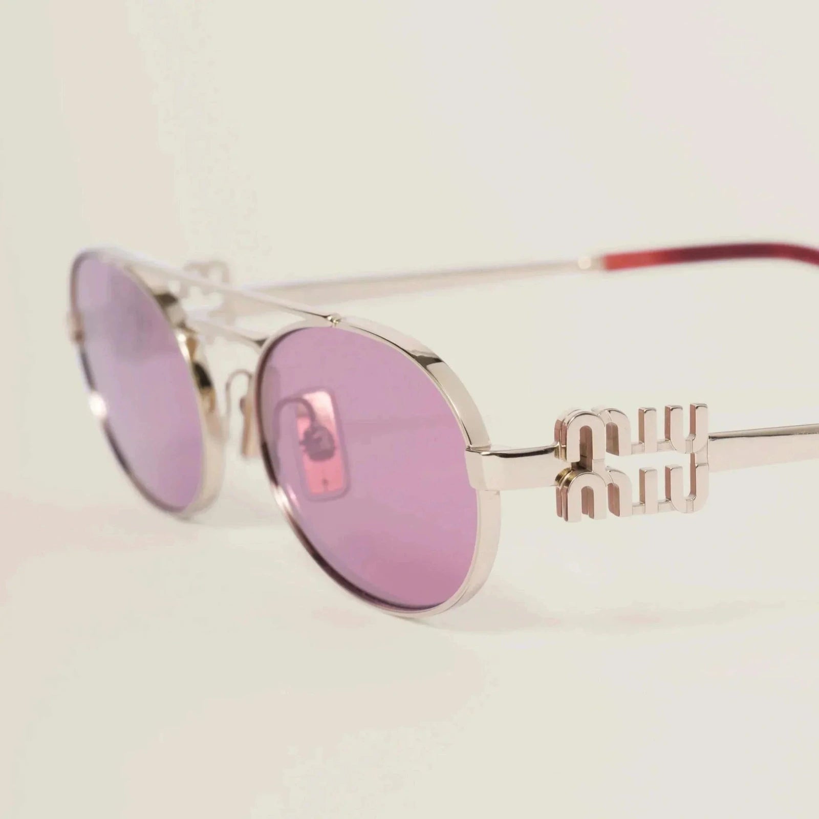 Miu Miu thin metal frame sunglasses with black plastic detailing, adjustable nose pads, and UVA/UVB protection.