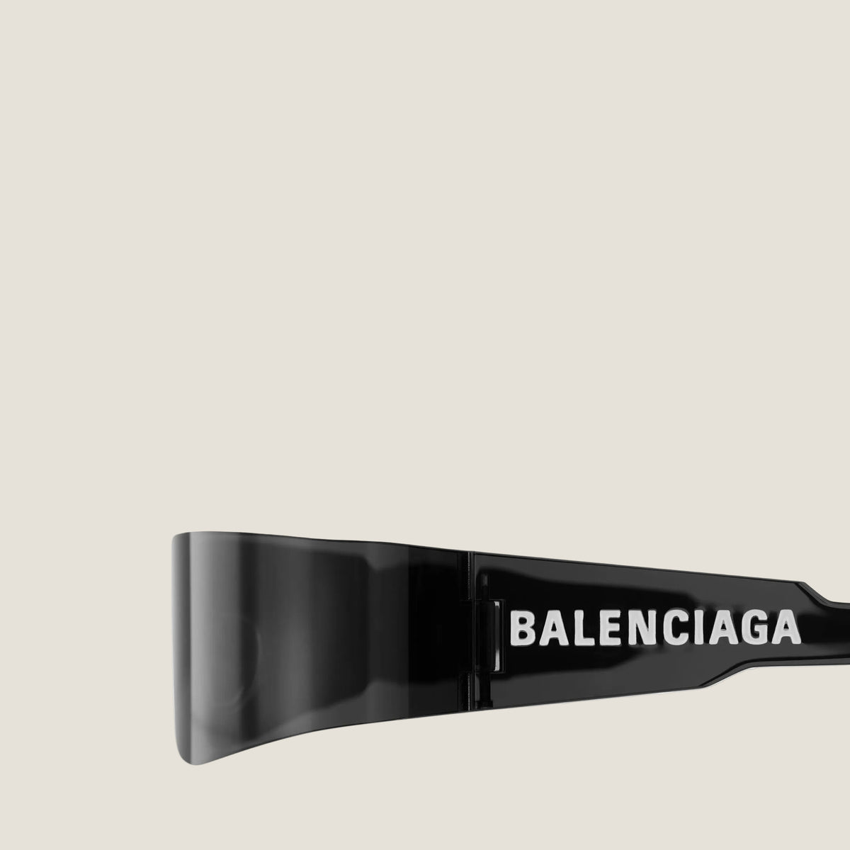 תקריב הכיתוב הלבן BALENCIAGA על זרוע שחורה לצד החזית הכהה של משקפי MONO
