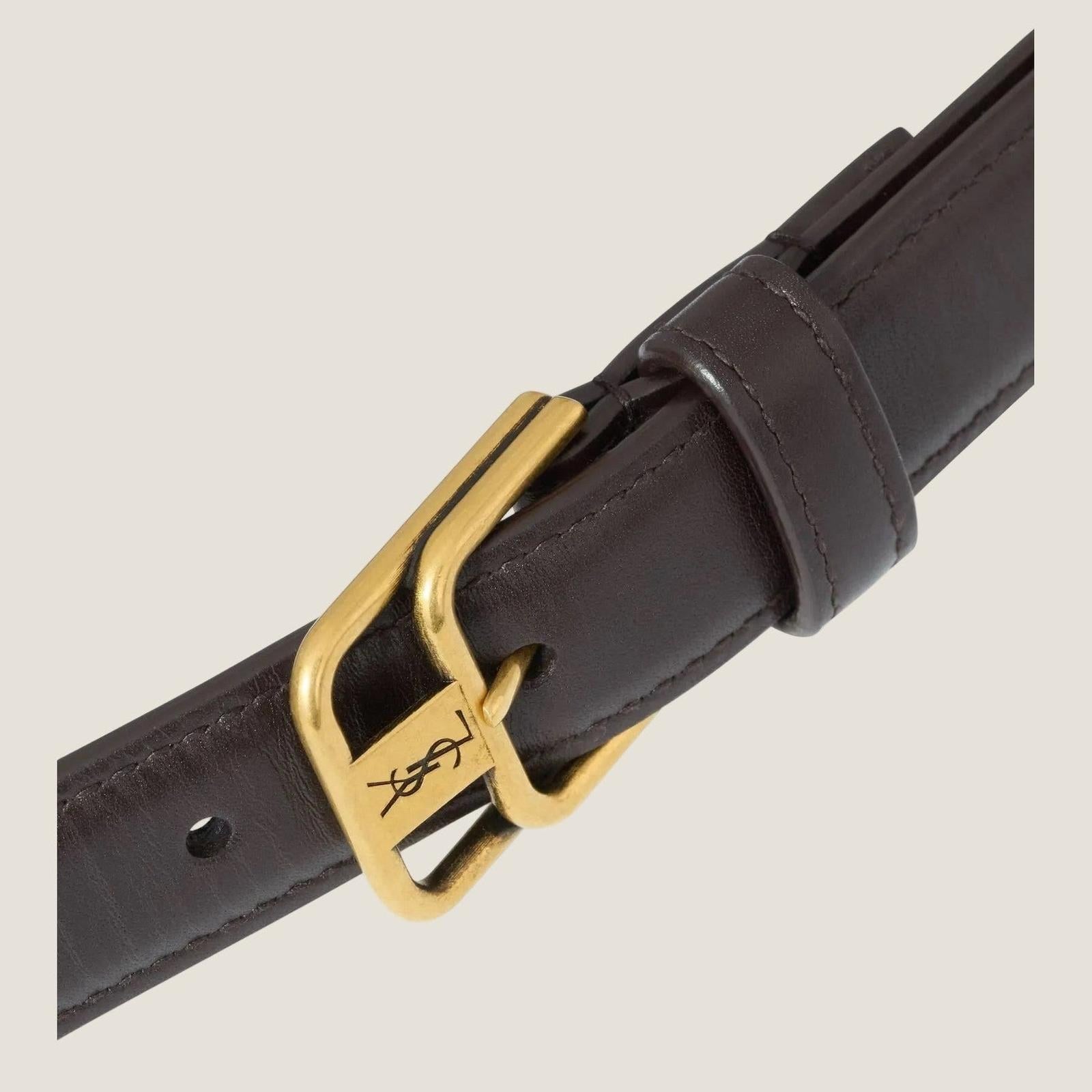 Image of תקריב האבזם הכפול הזהוב וחריטת YSL בחגורת CASSANDRE בחום כהה